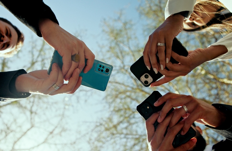 Two men and one woman are holding phones in their hands
