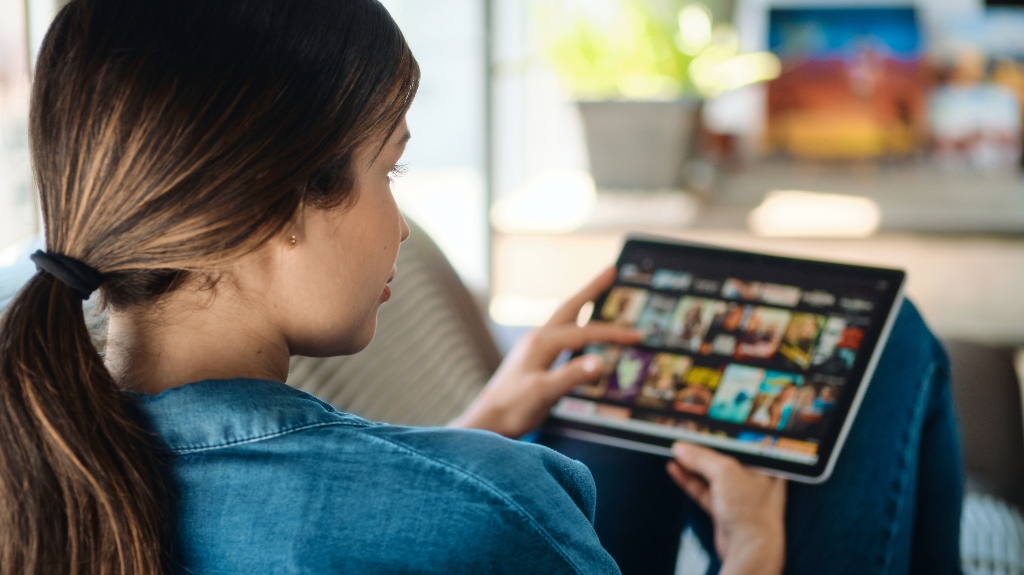 Woman Choosing Movie For Streaming On Tablet Computer
