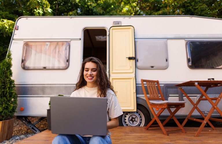 woman looks at a laptop near campground