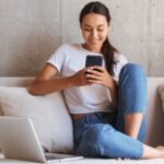 Happy woman is using phone and laptop