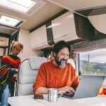 Woman cooking in the kitchen and adult man working on laptop computer